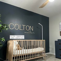 a baby crib in front of a wall with the name cotton written on it