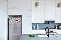 a modern kitchen with white cabinets and stainless steel appliances, including a refrigerator that has magnets on it