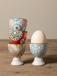 an egg sits in a bowl next to another one on a wooden table, which has been decorated with flowers and leaves