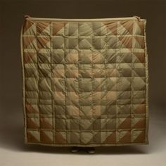 an old quilted blanket is on display against a gray background in this image, it appears to be made out of fabric