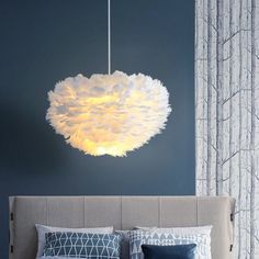 a bedroom with blue walls and a white light fixture hanging from the ceiling over the bed