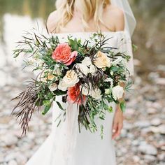 a woman holding a bouquet of flowers in her hand and wearing a white dress with an off the shoulder top