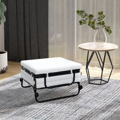 a white ottoman sitting on top of a rug next to a table and potted plant