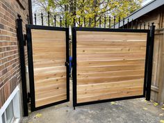 two wooden gates with black iron bars on the side of a brick building in front of a fence