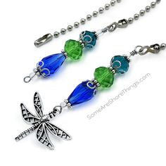 two necklaces with dragon charms hanging from it's sides, one is green and the other is blue