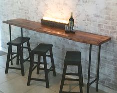 three stools and a table in front of a brick wall with lights on it