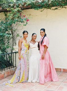 three women standing next to each other in dresses