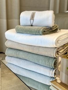 towels stacked on top of each other in front of a glass table with a plant