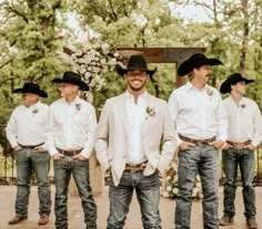 a group of men wearing cowboy hats standing next to each other in front of a fence