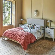 a bed sitting in a bedroom next to a window with two lamps on either side