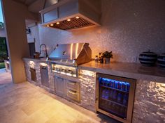 an outdoor kitchen with stainless steel appliances and lighting