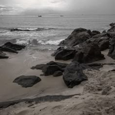 rocks on the beach with boats in the distance