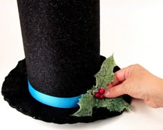 a black top hat with holly and blue ribbon