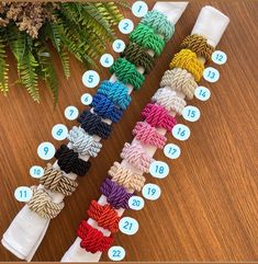 a bunch of different colored ropes sitting on top of a wooden table next to a plant