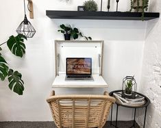 a laptop computer sitting on top of a white desk next to a potted plant