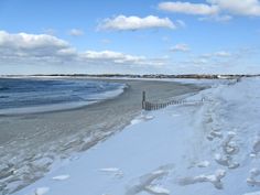 a beach covered in snow next to the ocean