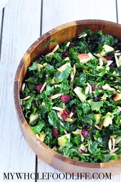 a wooden bowl filled with greens and nuts