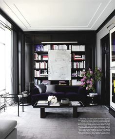 a living room filled with furniture and bookshelves next to a large painting on the wall