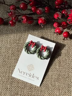 Embrace the festive spirit with our HOLIDAY HALO earrings, inspired by the timeless charm of Christmas wreaths. These handmade polymer clay earrings capture the essence of the season, featuring intricately twisted green wreaths adorned with delicate golden accents and topped with a classic red bow. Each pair of HOLIDAY HALO earrings is crafted with care to bring warmth and joy to your holiday wardrobe. Lightweight and comfortable, they're perfect for adding a festive touch to any outfit, whether Polymer Clay Christmas Wreath, Polymer Clay Wreath Earrings, Clay Holiday Earrings, New Years Clay Earrings, Holiday Clay Earrings, Easy Polymer Clay Earrings, Polymer Clay Christmas Earrings, Christmas Polymer Clay Earrings, Christmas Clay Earrings