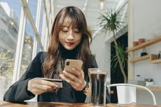 a woman sitting at a table looking at her cell phone