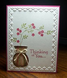 a greeting card with a vase and ribbon on the front that says thinking of you