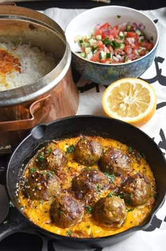 meatballs and rice in a skillet next to other food items on a table