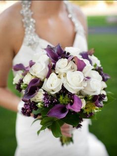 a bride holding a bouquet of white and purple flowers