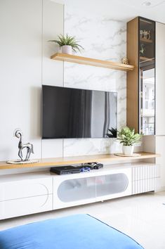 a flat screen tv sitting on top of a white entertainment center next to a blue bed