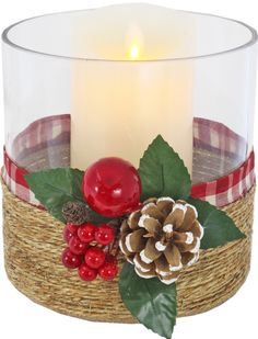 a candle is sitting in a basket with pine cones and berries