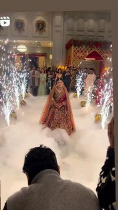 a bride and groom walking down the aisle at their wedding ceremony with fireworks in the background