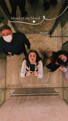 three people standing in an elevator with masks on their faces and looking up at the camera