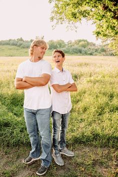 two young men standing next to each other in a field