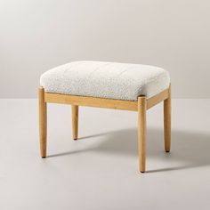 a wooden bench with a white upholstered seat and back cushion on the bottom