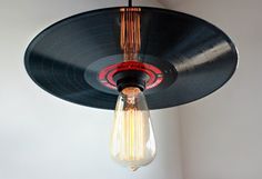 an old record player hanging from a ceiling light fixture with a bulb turned upside down