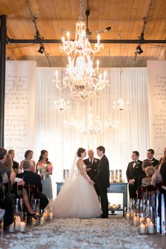 a bride and groom standing in front of their wedding guests at the alter with candles on the floor