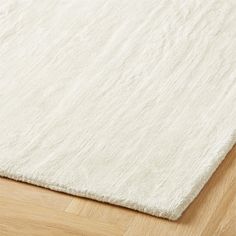 a white rug is laying on the floor with wood floors and hard wood planks