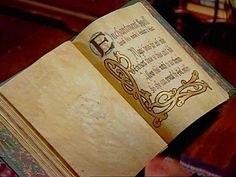 an open book with writing on it in a dark room next to a chair and table