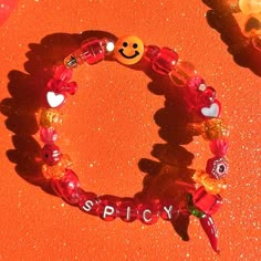 a bracelet that says spicy on it with charms and beads attached to it in front of an orange background