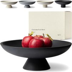 four apples in a black bowl on a white background, with the box behind them