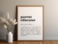 a white vase with flowers in it next to a framed poster that says parent educator