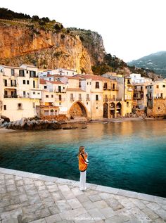 a woman standing on the edge of a body of water