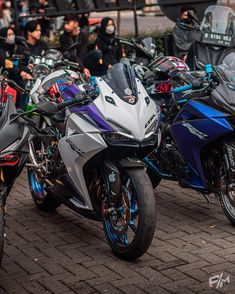 several motorcycles parked next to each other on a brick road with people in the background