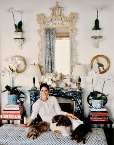 a woman sitting on top of a bed with two dogs in front of her and a mirror behind her