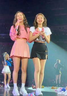 two girls standing on stage with microphones in their hands