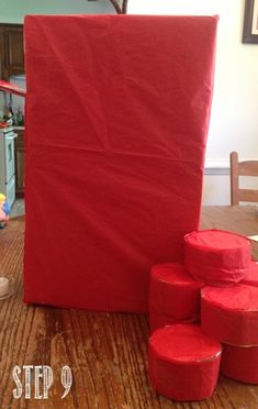 a group of red boxes sitting on top of a wooden floor next to a table