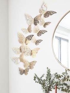 there are many butterflies on the wall next to a potted plant and a mirror