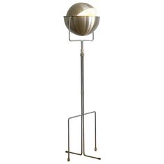 a metal floor lamp on a stand with a white light in the middle of it