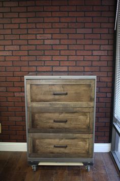 a wooden dresser sitting on top of a hard wood floor next to a brick wall