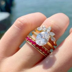 a woman's hand holding two rings with an oval shaped diamond