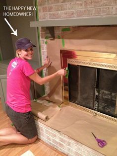 a woman in pink shirt sitting on the floor next to a fireplace with cardboard taped around it